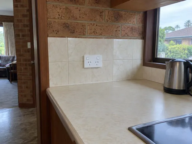 White double power point on tiled kitchen splashback above a bench in a brick home in Toukley
